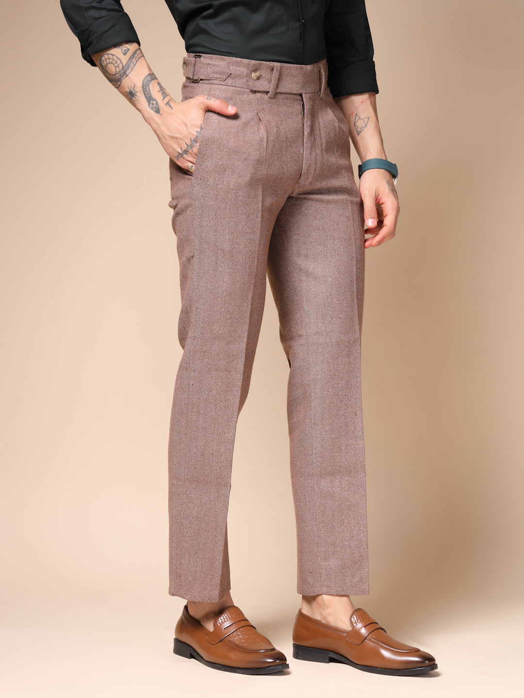 Person wearing brown pants and brown shoes on a beige background