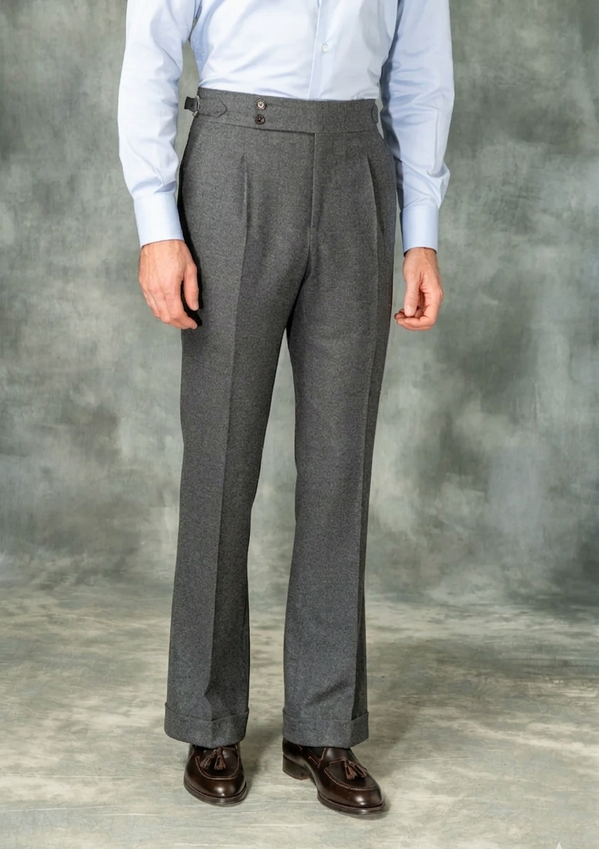 Person wearing gray pleated pants and a light blue shirt against a gray background
