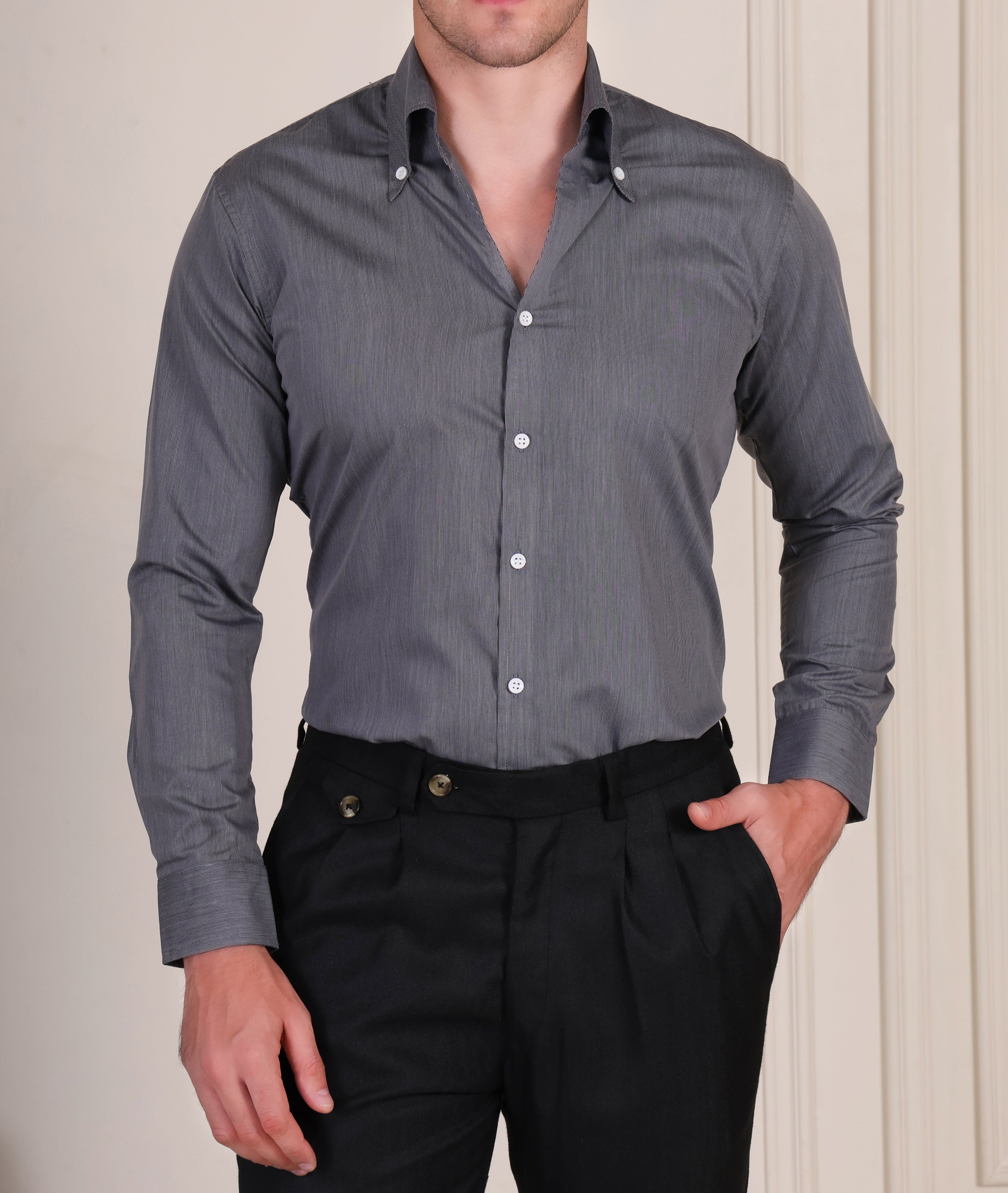 Man wearing a gray italian vega shirt and black gurkha pants against a neutral background